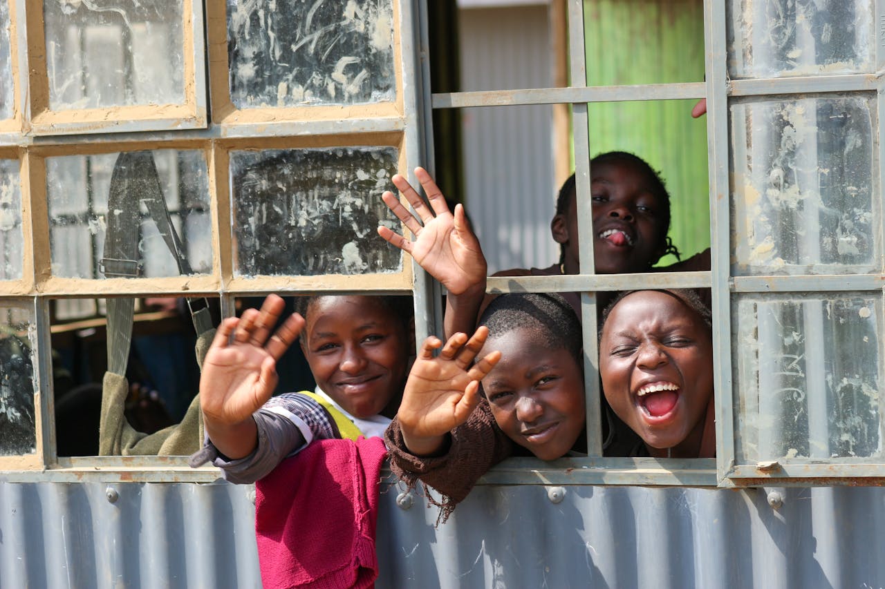 Four smiling children waving and having fun through a rustic window. Capturing joyful expressions.